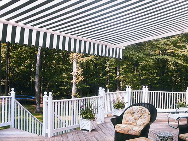 navy blue and white striped large awning extended over large deck with trampoline in the back
